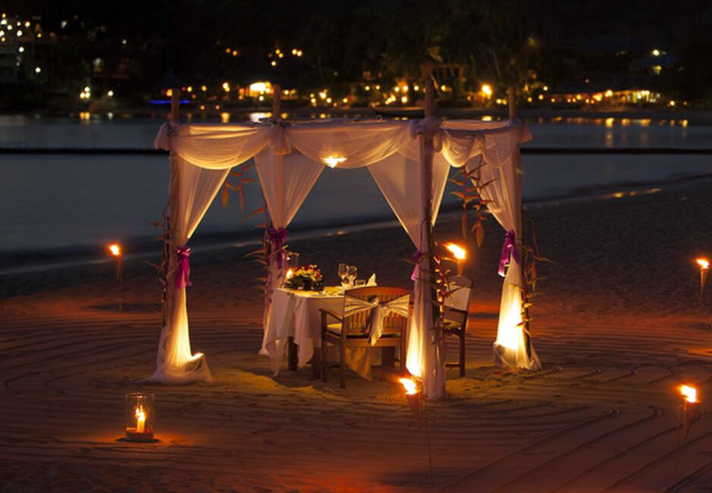 A candlelit dinner pavilion set on the beach at night